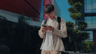 Genç ve Tatmin Olmuş Bir Okul Çocuğu, Smartphone 'unda Çevrimiçi Konuşmadan Hoşlanıyor. Koreli Öğrenciler Dışarıda Neşeli İnternet Bağlantısı
