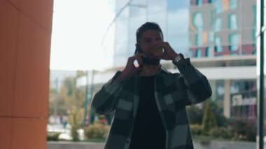 Kendine güvenen Amerikalı erkek, elinde fincanla kentteki akıllı telefonu üzerinden canlı bir tartışmaya girişiyor. Bir Şehir Ayarında Telefonda Yakışıklı Erkek Tarzı ile Sohbet