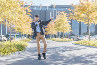 A happy white-collar worker enjoys a moment of celebration, dancing outdoors against the backdrop of an office building, expressing pure career satisfaction. clipart