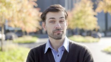 Sonbahar arkaplanı olan ve kameraya özgüvenle bakan ciddi bir ofis çalışanının portresi. İş kıyafetleri içinde, profesyonellik yayıyor..