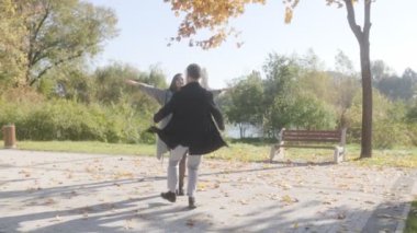 Sonbahar sezonu boyunca güzel bir parkta bir çift kucaklaşma, ilişkilerini kutlamak için. Neşeleri ve sevgileri altın yapraklara ve sonbahar atmosferine karşı parlıyor..