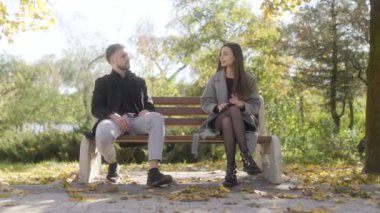 Bir adam ve bir kadın bir bankta sevgiyle otururlar, birbirlerine sarılırlar. Sonbahar atmosferi ve renkli yapraklar samimi ve romantik bir ortam yaratır..