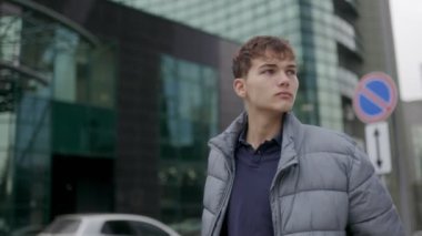 Şık ceketli genç bir çocuk, şehir zeminine yaslanmış, kendine güvenen bir ifadeyle şehir ortamını keşfediyor, sıradan gençlik tarzını sergiliyor..