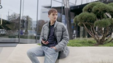 Bir gencin telefonuyla kablosuz kulaklıkla müzik dinlediği kentsel yaşam tarzı. Sakin ve sıradan, modern dijital rahatlığı yansıtan.