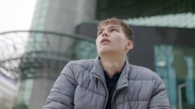 Üniversite kampüsündeki genç bir öğrencinin portresi, görünüşte yorgun ve sıkılmış. Onun ciddi ifadesi ve yorgun duruşu yoğun çalışmanın zorluklarını yansıtır.