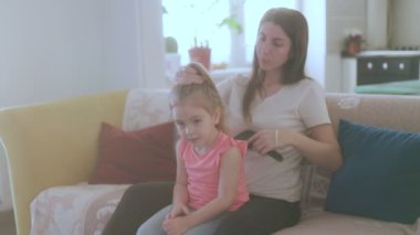 Bir kadın kızına rahat bir evde saçını tarar, ebeveynliğin özünü yakalar ve aile anlarının güzelliğini yakalar..