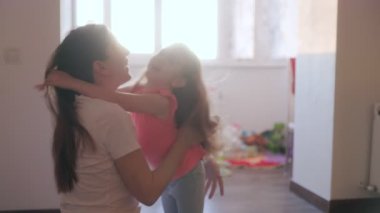 Mutlu anne ve kız birlikte güler parlak bir oturma odasında, aile sevgisini, kaliteli zamanı ve sıcak bir ev ortamını vurgulayarak.