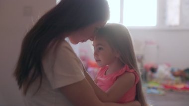 Birbirlerine çok yakın bir aile sahnesi. Genç bir Amerikalı anne ve kız, oturma odalarının rahat ortamında birlikte çok değerli zaman geçiriyorlar..