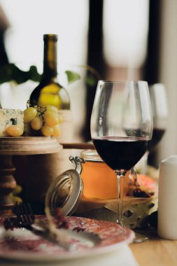 Bir şişe şarap masanın üzerinde bir bardak şarabın yanında. Masa yemek ve şarap kadehleriyle dolu.