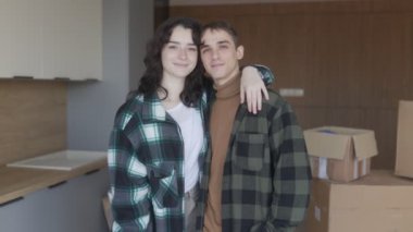 Yeni bir dairede kameraya bakan mutlu bir aile çifti. İkisi de siyah saçlı sıradan gömlekler giyip yeni bir hayata başlayacakları için heyecanlılar..