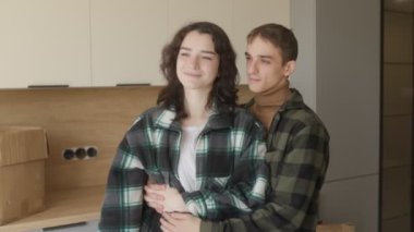 Neşeli bir aile yeni evlerinde mutlu bir kucaklaşmayı paylaşıyor. Anahtarları elinde tutan kadın, yenilenmiş alanı keşfederken onları heyecan içinde kocasına gösteriyor..