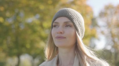 Sonbahar kıyafetli bir kadın dışarıda güneşli bir günün tadını çıkarıyor. Sıcak bir sonbahar gününde parkta bir kadının portresi.