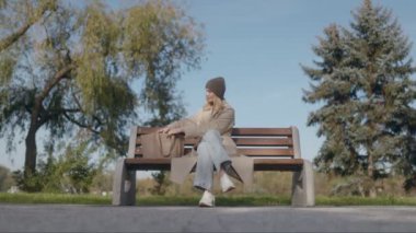 Sakin bir sonbahar gününde, sarışın bir kadın parktaki bankta okumak için kitabını çıkarır. Şapka takmış, sonbahar renklerini ve açık hava havasını seviyor..