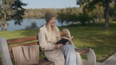 30 yaşında, sarışın bir Amerikalı kadın sonbaharda bir bankta oturuyor. Bir kitap okuyor ve mutlu bir şekilde gülümsüyor, açık havanın tadını çıkarırken şapka takıyor..