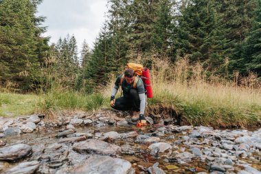 Trailside Oasis American Walk in the Heart of Nature, Serene Forest Stream 'den şişesini dolduruyor rahatlatıcı bir yolculukta.