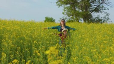 Mutlu anne ve çocuk tarımda kolza tohumu ile koşuyor. Çiftçilik ailesi ve annelik kavramı, mutlu aile çocukları birlikte koşuyor.