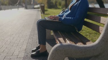 Sonbaharda parktaki bankta dizüstü bilgisayarında yazmaya odaklanmış genç bir kızın portresi. Yanında kitaplarla, sakin bir ortamda açık hava eğitimini kucaklıyor..