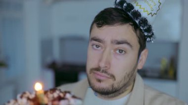 Gerçek bir yalnızlık anında parti şapkalı bir adam elinde mumla doğum günü pastası tutarken evinde sessizce kutlama yapar..
