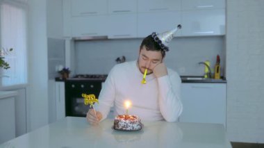 Masada oturan orta yaşlı bir adamla birlikte bir evde doğum günü kutlaması. Pasta ve şenlikli aksesuarlarla sessizce kutlanıyor..