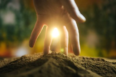 Yumuşak güneş ışığı içerisinden süzülüp dokuları aydınlatırken ve dünyayla doğal güzellik arasında huzurlu bir bağ kurarken eller yavaşça zengin toprağa bastırır..