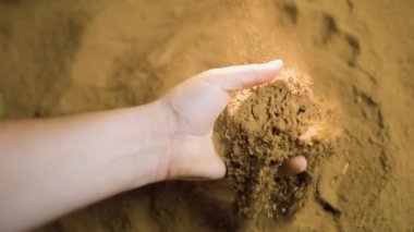 Ellerin gevşek toprağı elleyip, dokusunu ve bileşimini ortaya çıkardığı görülüyor. Bu meşgul edici aktivite doğa ve dünya ile yakın bir bağlantı gösteriyor..