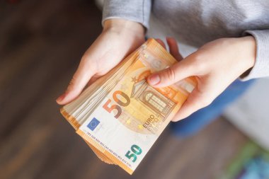Avro banknotlarını sunan eller, Avrupa ekonomisi ve zenginlik yönetimi bağlamında mali başarı, gelir ve para güvenliğini sembolize etmektedir.