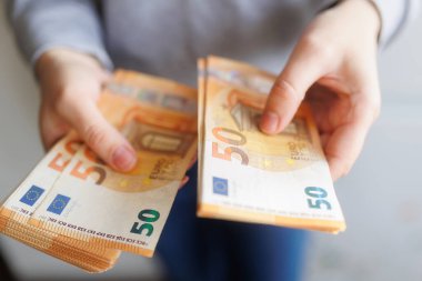 Avro nakitini tutan, kişisel zenginliği, mali planlamayı ve avro para birimi sisteminin somut yönünü temsil eden ellerin yakın çekimi.
