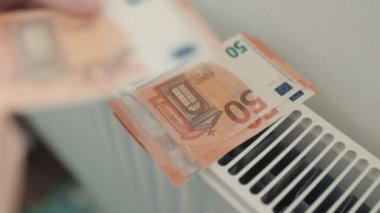 Bir kişi tarafından sayılan ve radyatöre yerleştirilen Euro banknotları, enerji faturalarının artan baskısını ve ısıyı korumanın yüksek maliyetini göstermektedir..