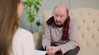 Terapist terapi seansı sırasında hastayı dikkatle dinler. Oda sakin, tartışma ve iyileşme için rahat bir ortam sağlıyor..