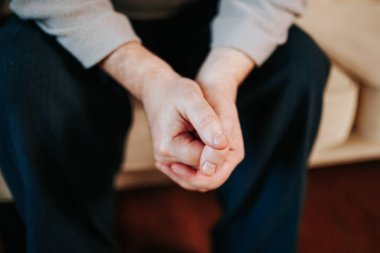 Bir insan koltuğa oturur ve elleri rahat bir şekilde birbirine kenetlenir. Ilık iç mekan, odadaki sükunet ve tefekkür duygusunu arttırır..