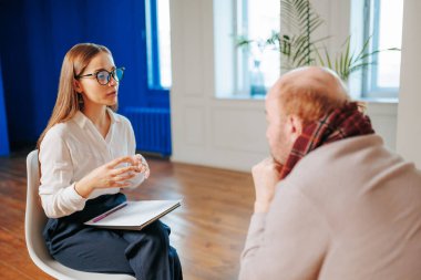 Profesyonel bir konuşma çağdaş bir ofiste yapılır. Gözlüklü bir kadın, karşısında oturan müşterisiyle diyaloğu kolaylaştırıyor..