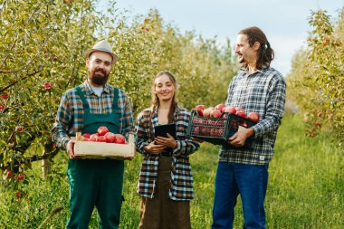 Ön manzara mutlu bir gülümseme. Meyve bahçesinde üç çiftçi kameraya bakıyor. İçinde ekinler ve elektronik tablet olan kutuları tutuyor. Erkekler ve kadınlar yaptıkları işten memnunlar. Hasat toplandı..