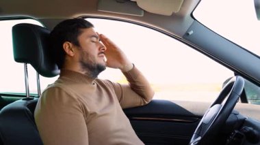 Yan görüş genç erkek sürücü gözlerini kapattı ve elleri direksiyonda diğeri de alnında dinleniyor. Verimli bir şekilde çalışmak için, iyi bir dinlenmeye ihtiyacın var. Adam yorgun..