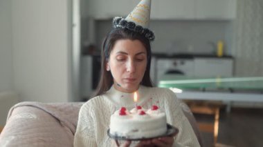 Bir Amerikalı kadının doğum gününü yalnızlık içinde kutlaması, evinde pasta ve mumlarla birlikte bir kanepede oturması, düşünceli bir an..