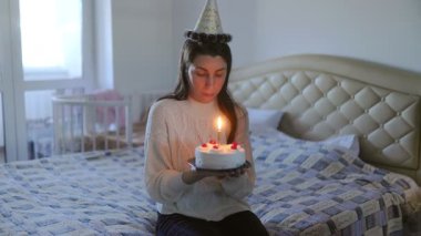 Bir Amerikalı kadının özel anı, elinde doğum günü pastasıyla yatağında tek başına oturmuş, evde sessizce kutlama yaparken hayatını yansıtıyor..