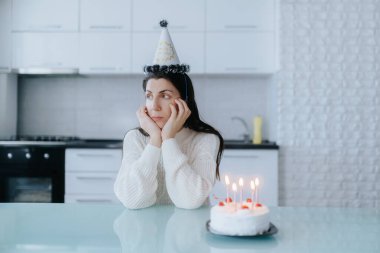 Mutfağında yalnız bir kadın sessiz bir doğum gününü mumlarla süslenmiş küçük bir pastayla kutluyor. Dokunaklı bir kişisel yansıma anı yaşıyor..