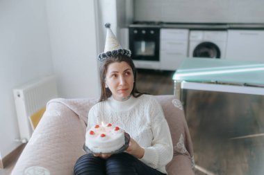 Bir Amerikalı kadının doğum gününü yalnızlık içinde kutlaması, evinde pasta ve mumlarla birlikte bir kanepede oturması, düşünceli bir an..