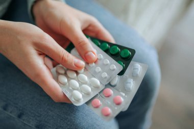İki el, farklı renkler ve tablet şekilleri de dahil olmak üzere çeşitli ilaçlardan oluşan su toplayan paketleri rahat bir ortamda duruyor..