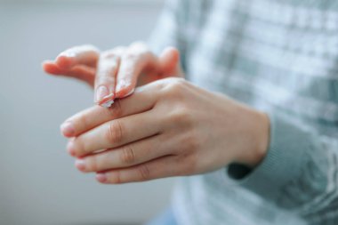 Bir insan eline krem sürerek nazikçe masaj yapar ve susuzluğa odaklanır. Sıcak, davetkar bir mekanda oturuyorlar, özgüven ve rahatlama sergiliyorlar..