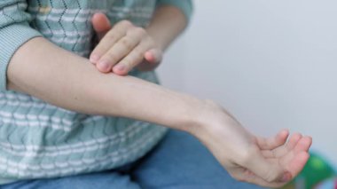 Tanınmayan bir kız, genç bir kadın eline ve bileğine krem sürüyor. Cilt bakımı. Kuru ve soğuk havalarda nemlendirme çok önemlidir. Kremli kadın kolları. Kadın elinin bakımı.