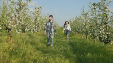Mutlu genç bir kadın çiçek açan bir meyve bahçesinde erkek arkadaşına biniyor. Sevgi, kahkaha, bağ ve saf neşeyle dolu güneşli bir günün tadını çıkarıyor..