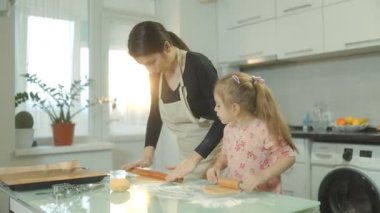 Güneşli bir ev mutfağında, bir anne ve kız, ev yapımı kurabiyeler için taze hamur sararken, aile ve mutfak yaratıcılığının neşesini yakalıyorlar..