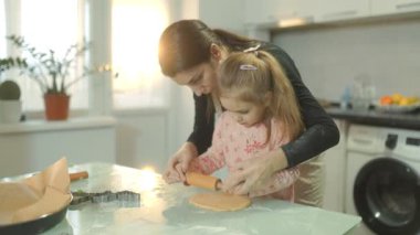 Pişirme yoluyla kaynaşan bir anne ve kız, sıcak bir ev mutfağında taze hamur rulosu yaparak, aile zamanının ve mutfak keşiflerinin neşesini vurguluyor..
