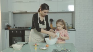 Anne ve küçük kızı mutfakta kaliteli zaman geçiriyorlar, bisküvi hamurunu aşk ve kahkahalarla bir tencerede hazırlıyorlar..