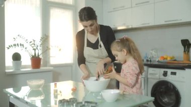 Bir anne ve kızı için iç açıcı bir aile anı. Bir tencerede malzemeleri karıştırıp evde birlikte bisküvi hazırlıyorlar..