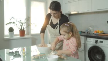 Anne-kız olarak aile geleneği canlanıyor. Sıcak mutfaklarındaki tencerede bisküvi hamuru yapmak için birlikte çalışıyorlar..