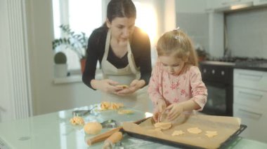 Anne ve kızının kurabiye hamuru şekillendirdiği rahat bir mutfak sahnesi. Kahkahalar ve yaratıcılık fırında pişerken birbirine bağlanır..