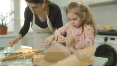 Anne ve kızının kurabiye şekillendirdiği neşeli bir mutfak sahnesi. Eğlenceli ve neşeli kahkahalarla dolu yaratıcı ve bağlayıcı bir deneyim..