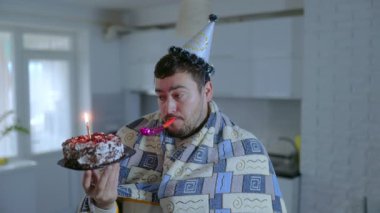 Pasta tutan, ıslık çalan, battaniyeye sarılmış, hüzün ve hayal kırıklığı hisseden yalnız sakallı bir adamın olduğu resmi bir doğum günü sahnesi..