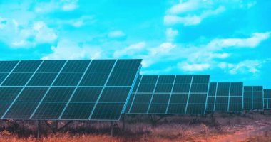 Zaman atlaması, açık doğadaki geniş bir güneş paneli alanını bulutlu canlı mavi gökyüzü altında gösteriyor, dinamik hareketlerle yenilenebilir enerji üretimini yakalıyor..
